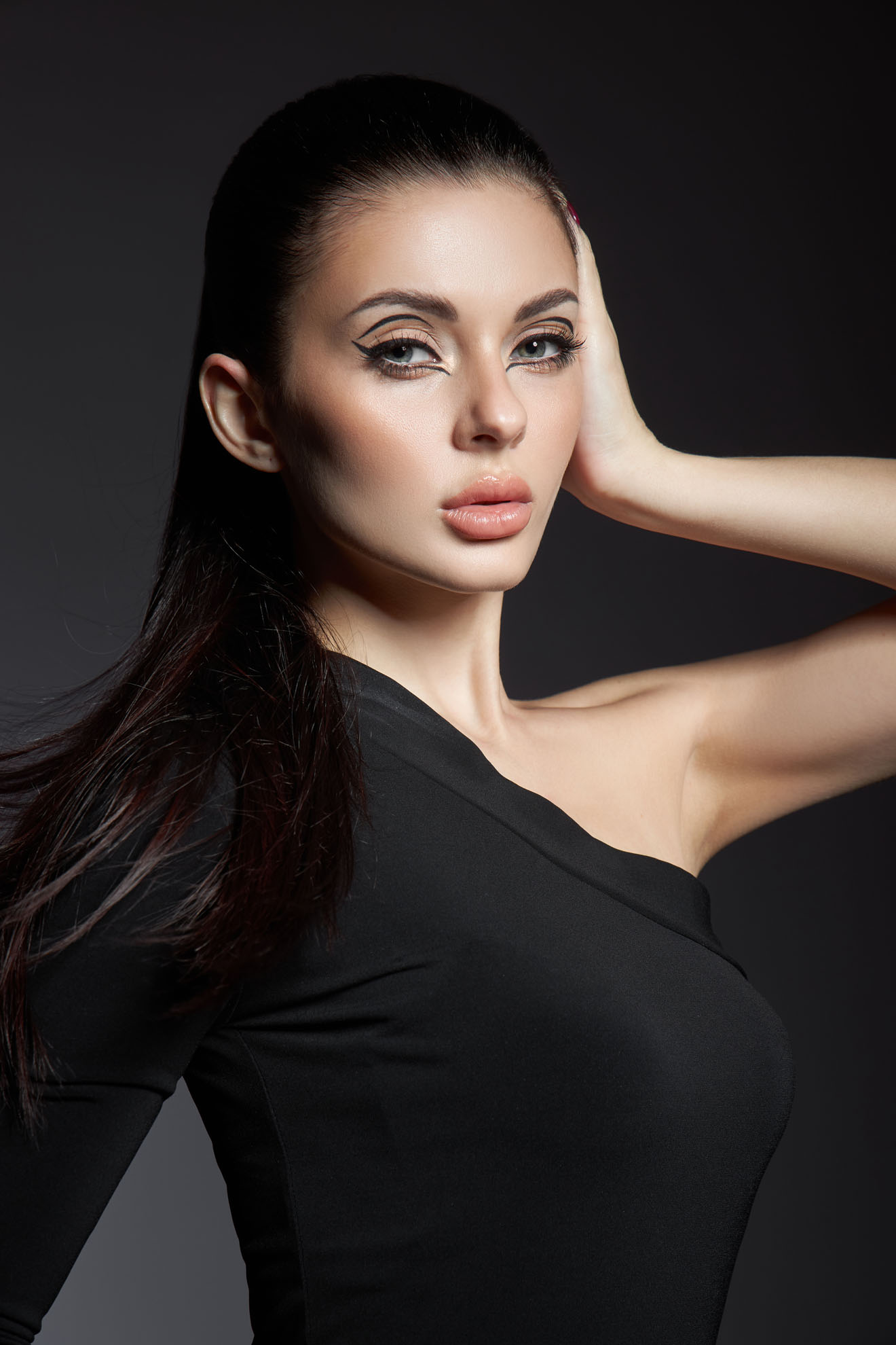 Classic makeup on woman face, beautiful big eyes. Fashion Perfect makeup, expressive eyes on girl face, smooth black eyebrows, licked brunette hair. Portrait woman on dark background